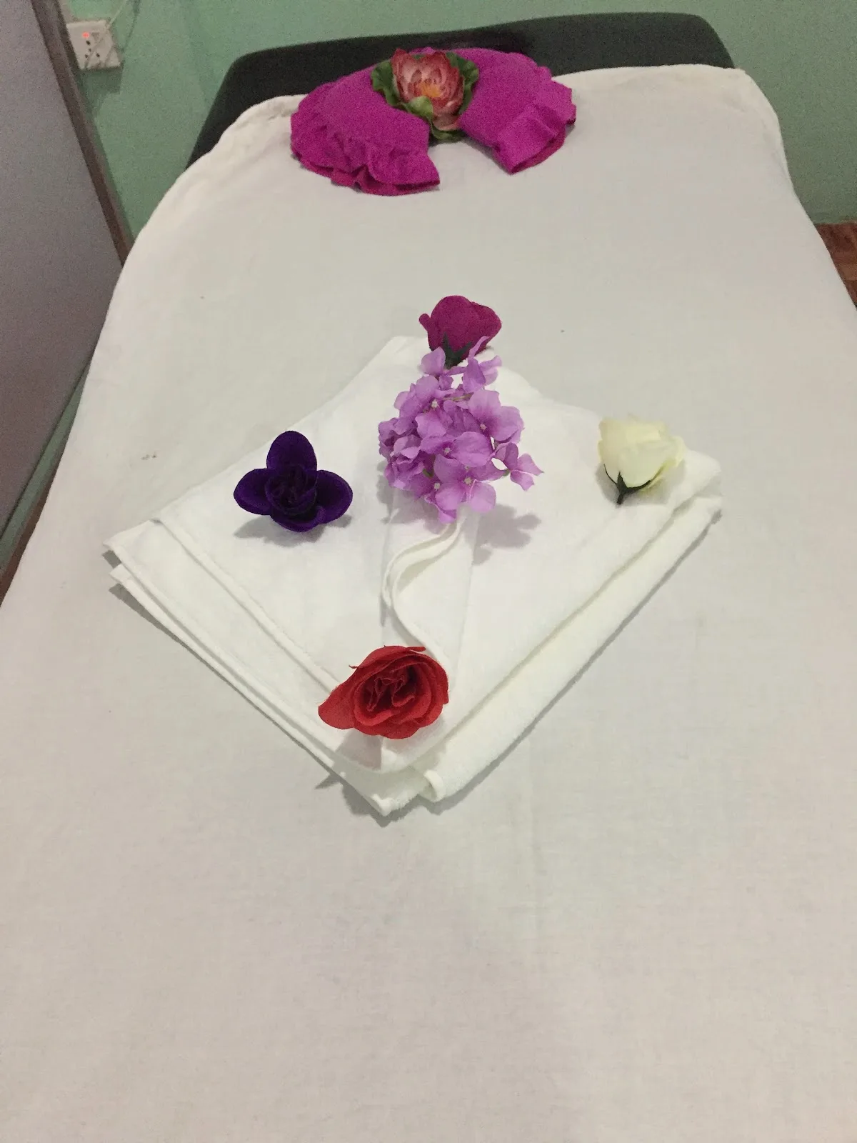 Sakura Spa treatment cabin: white linen, rose and orchid blossoms folded on the bed
